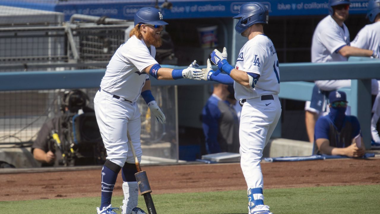 Los Angeles Dodgers' Justin Turner, left, celebrates A.J. Pollock's solo home run during the first inning of a baseball game against the Los Angeles Angels in Los Angeles, Sunday, Sept. 27, 2020. (AP Photo/Kyusung Gong)