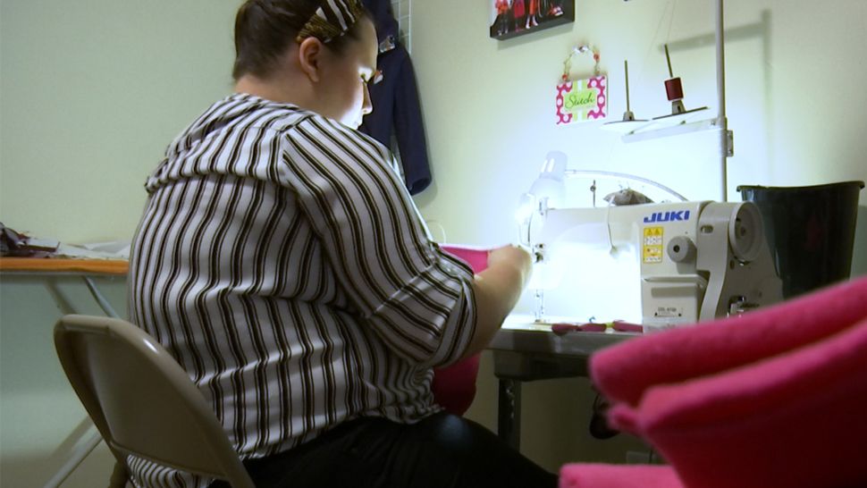CCAD graduate sewing at her machine