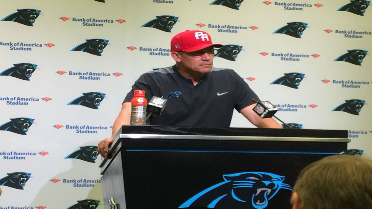 Panther coach Ron Rivera addresses the media wearing a red Puerto Rico hat