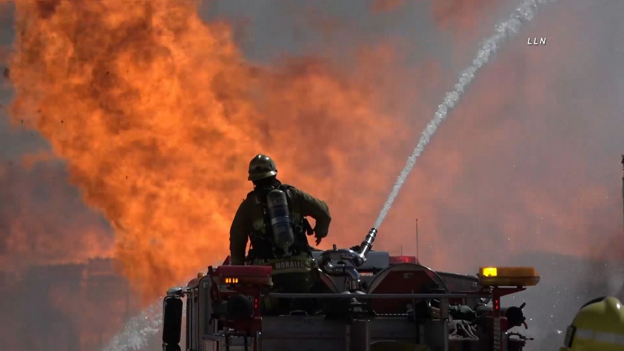 A firefighter battles a large fire at a Carson commercial facility at 16325 S. Avalon Blvd in Carson, Calif. (Spectrum News 1)