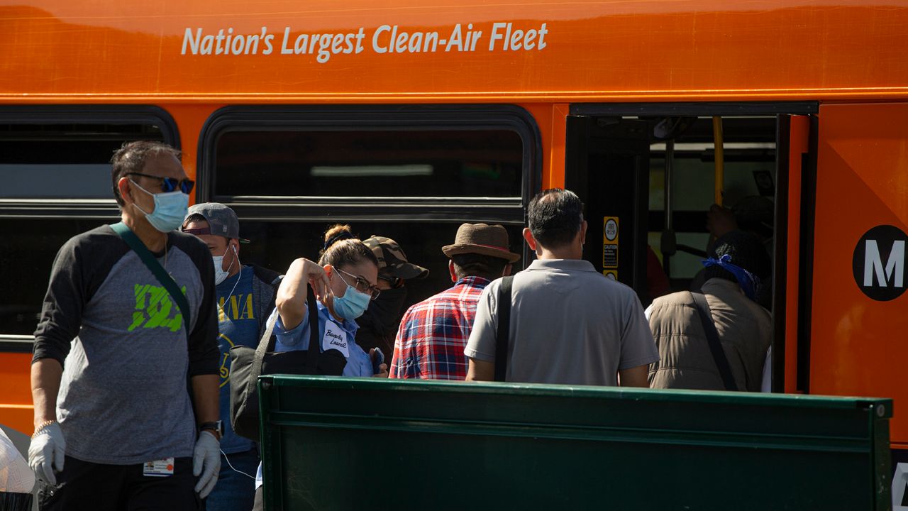 In this May 14, 2020, file photo, Los Angeles Metro commuters board a bus in Los Angeles. (AP Photo/Damian Dovarganes)
