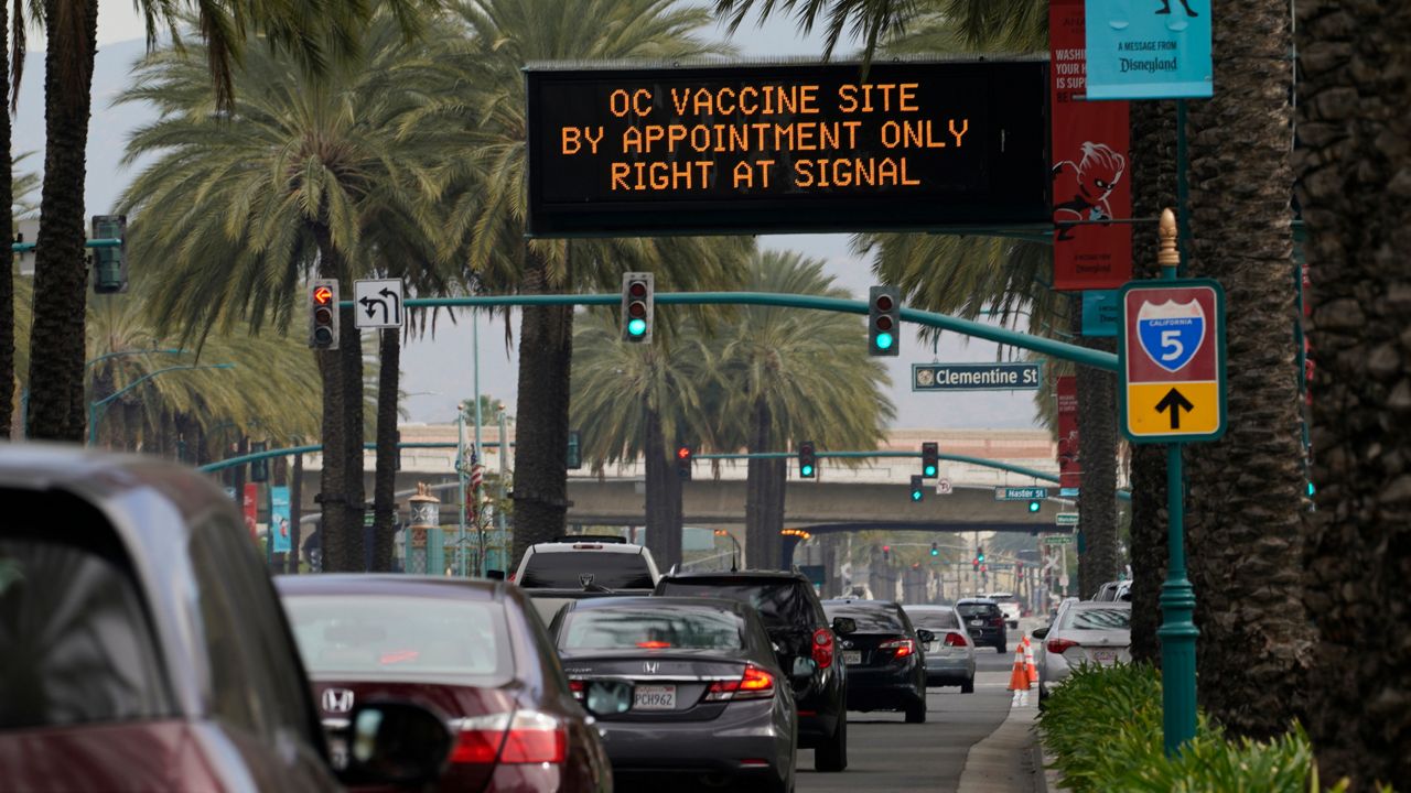 Vehicles queue up outside the Disneyland Resort parking for a COVID-19 vaccine in Anaheim, Calif., Wednesday, Jan. 13, 2021. (AP Photo/Damian Dovarganes)