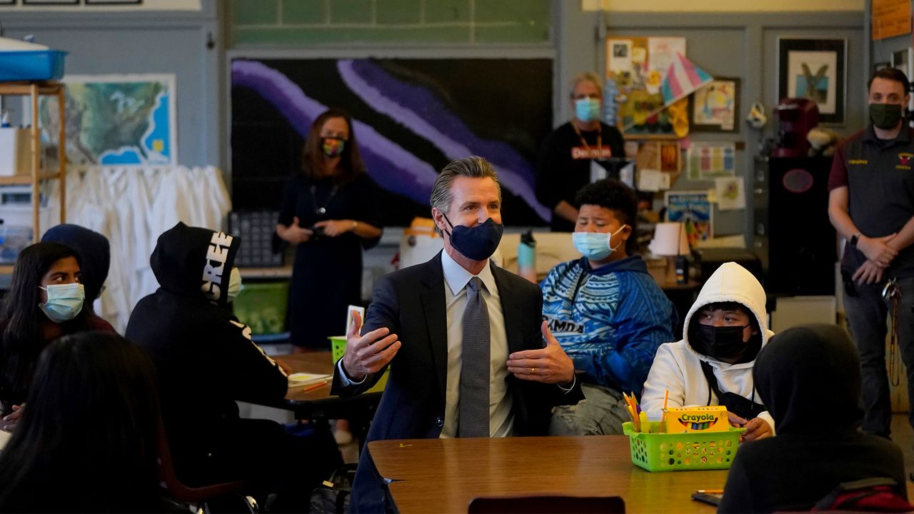 Gov. Gavin Newsom, middle, speaks to students in a seventh grade science class at James Denman Middle School in San Francisco, Friday, Oct. 1, 2021. California has announced the nation's first coronavirus vaccine mandate for schoolchildren. (AP Photo/Jeff Chiu)