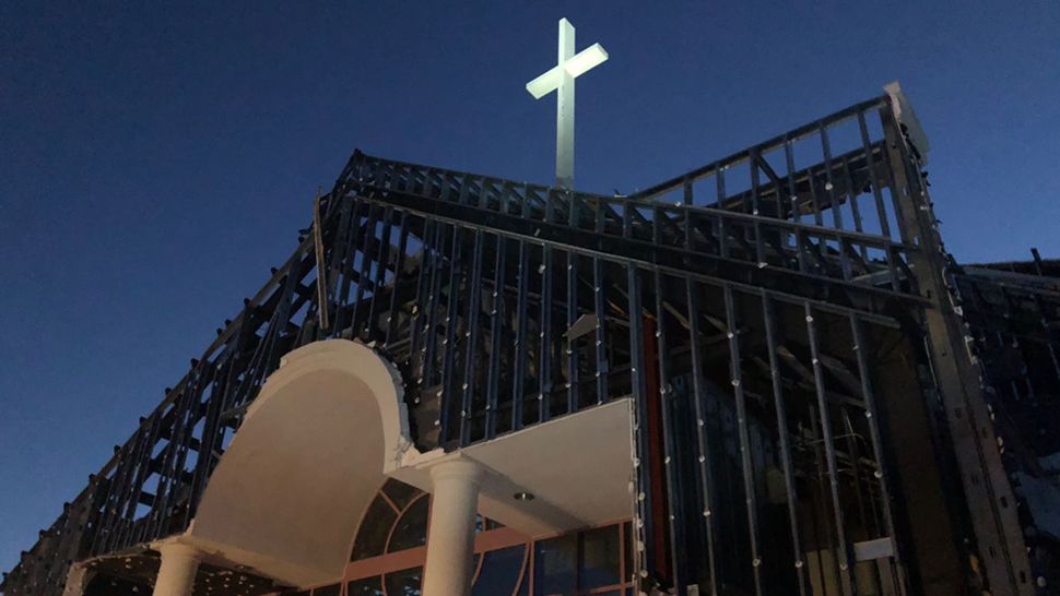 The whole front of the Central Pentecostal Ministries was blown apart by destructive winds of Hurricane Michael, however, the very top of the church sits a cross that is seemingly unscathed by the storm. (Jeff Allen/Spectrum News)