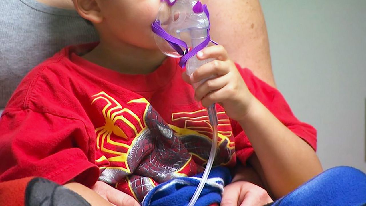 A child uses into an oxygen mask. 