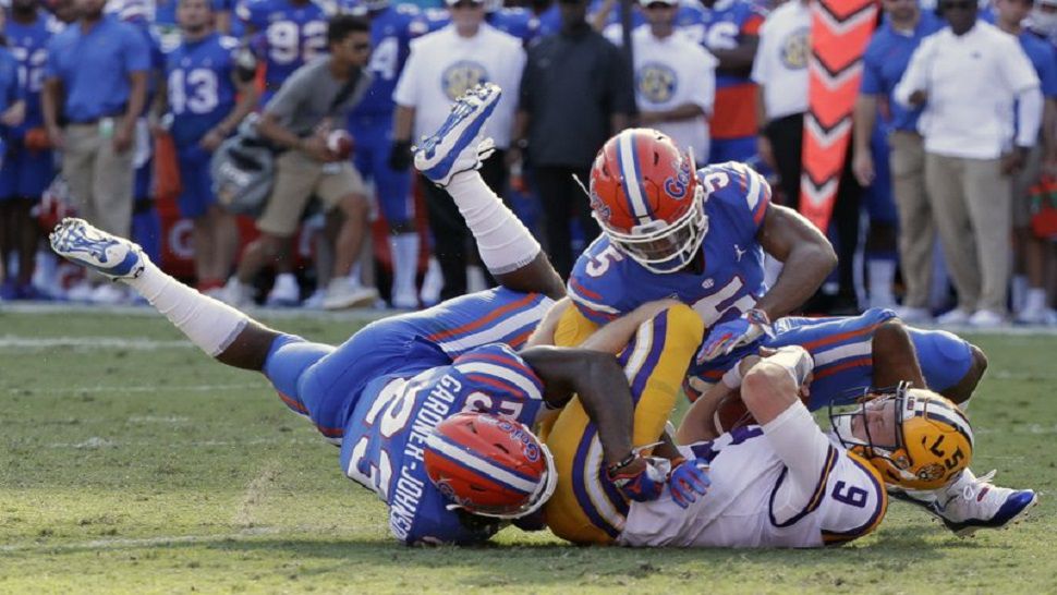 LSU quarterback Joe Burrow is tackled by Florida defensive back Chauncey Gardner-Johnson (23) and defensive back CJ Henderson, right, after running for a first down.  The Gators defense forced three turnovers in their 27-19 win. (AP Photo/John Raoux)