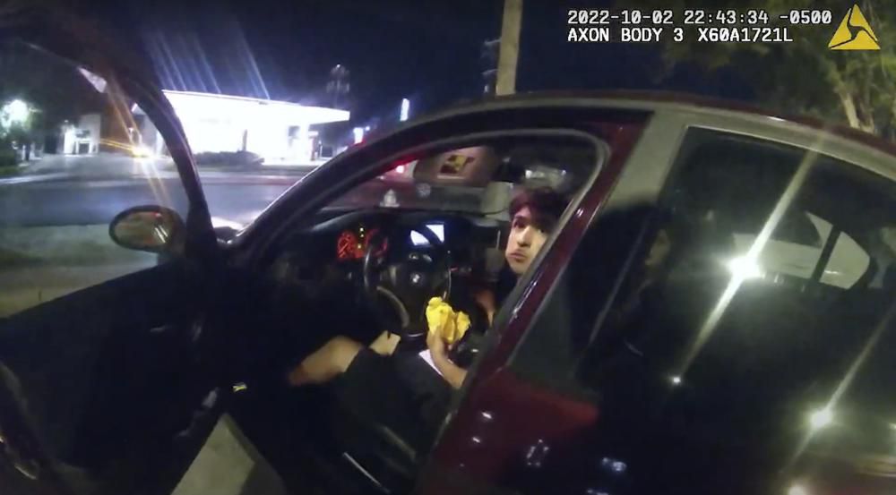 In this image taken from Oct. 2, 2022 police body camera video and released by San Antonio Police Department, Erik Cantu looks toward San Antonio Police officer James Brennand while holding a hamburger in a fast food restaurant parking lot as the officer opens the car door in San Antonio, Texas. Brennand opened fire several times wounding the unarmed teenager as he drove away. Brennand was fired after the shooting, police training commander Alyssa Campos said in a video statement released Wednesday, Oct. 5, 2022. (San Antonio Police Department via AP)