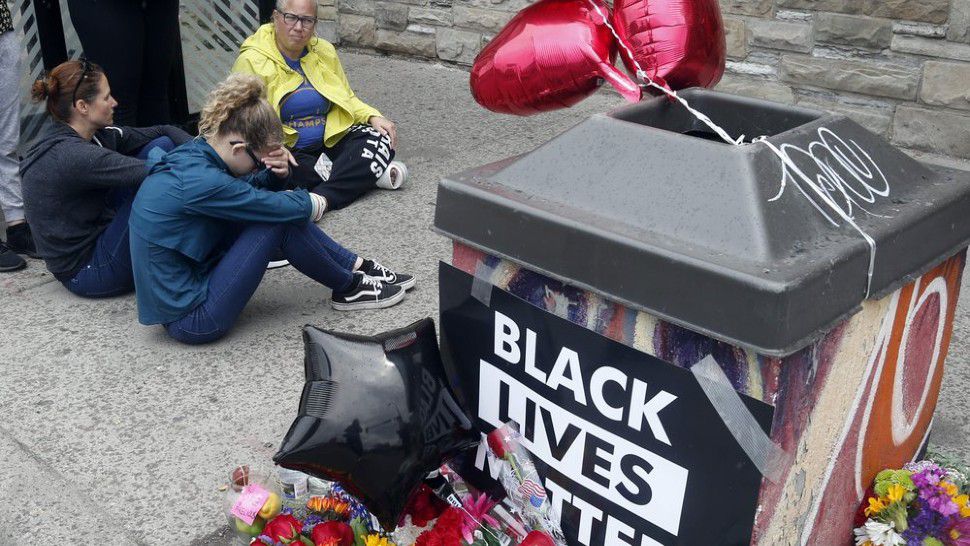 Mourners gather near the site of the death of a man, Tuesday, May 26, 2020, who died in police custody Monday night in Minneapolis after video shared online by a bystander showed a white officer kneeling on his neck during his arrest as he pleaded that he couldn't breathe. (AP Photo/Jim Mone)