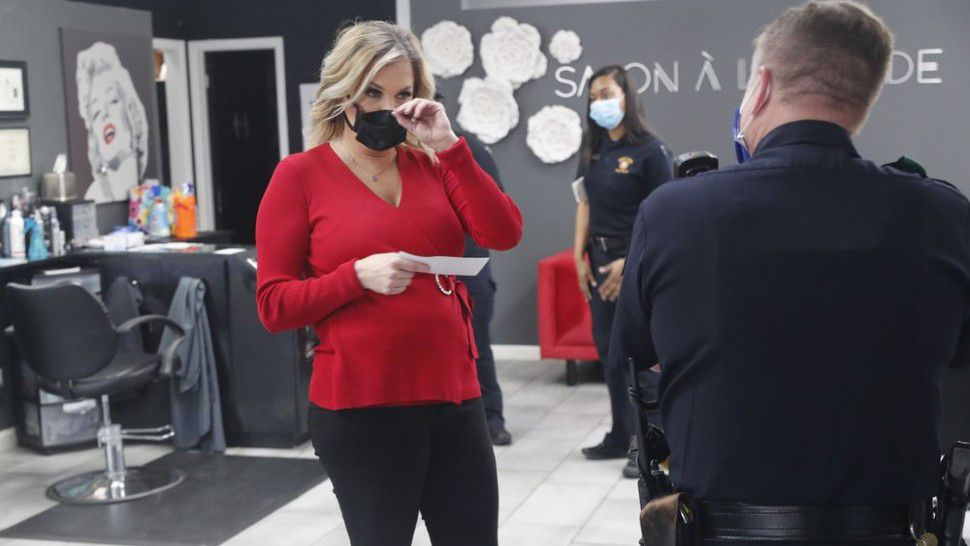 Salon owner Shelley Luther holds a citation and speaks with a Dallas police officer after she was cited for reopening her Salon A la Mode in Dallas, Friday, April 24, 2020. Hair salons have not been cleared for reopening in Texas. Luther was asked by officials to close and was issued a citation when she refused. Luther said she will remain open for business. (AP Photo/LM Otero)