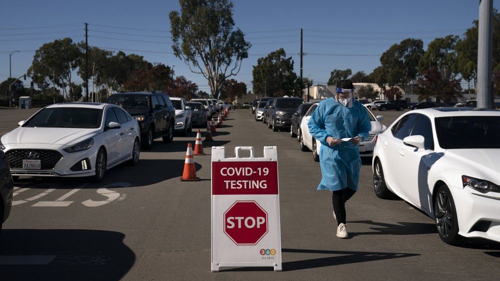 Student nurse Ryan Eachus collects forms as cars line up for COVID-19 testing at a testing site set up the OC Fairgrounds in Costa Mesa, Calif., Monday, Nov. 16, 2020. (AP Photo/Jae C. Hong)