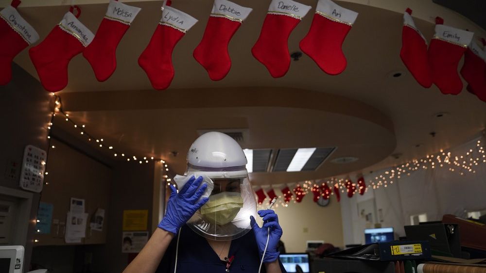 Registered nurse Romina Pacheco disinfects her powered air purifying respirator after tending to a patient in a COVID-19 unit decorated with Christmas stockings with nurses' names written on them at Mission Hospital in Mission Viejo, Calif., Monday, Dec. 21, 2020. (AP Photo/Jae C. Hong)