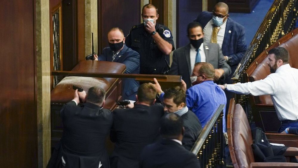 U.S. Capitol Police with guns drawn stand near a barricaded door as protesters try to break into the House Chamber at the U.S. Capitol on Wednesday, Jan. 6, 2021, in Washington. (AP Photo/Andrew Harnik)