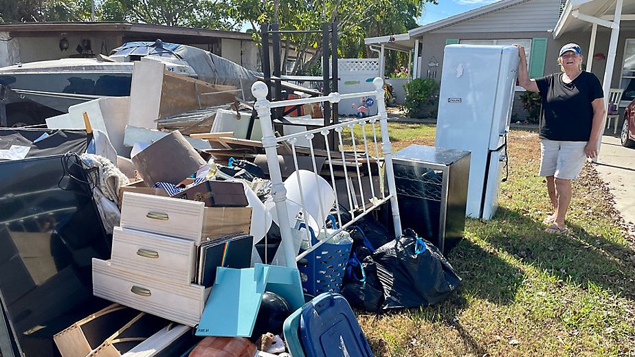 Kate Mullin stands next to most of her possessions that were destroyed by Hurricane Helene. (Spectrum Bay News 9/Erin Murray)