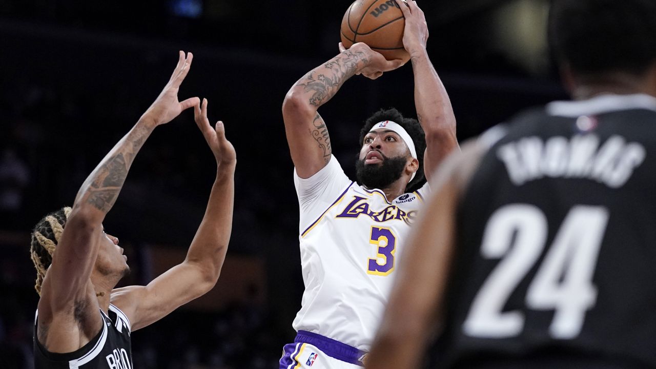 Los Angeles Lakers forward Anthony Davis, center, shoots as Brooklyn Nets forward Nicolas Claxton, left, defends and guard Cam Thomas watches during the first half of a preseason NBA basketball game Sunday, Oct. 3, 2021, in Los Angeles. (AP Photo/Mark J. Terrill)