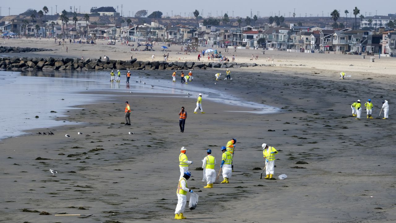 Workers in protective suits clean the contaminated beach after an oil spill on Oct. 6, 2021, in Newport Beach, Calif. (AP Photo/Ringo H.W. Chiu)