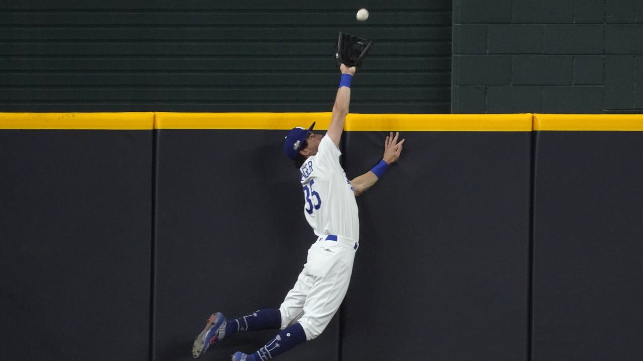 Los Angeles Dodgers' Cody Bellinger slams into the outfield wall and makes the catch as he robs San Diego Padres' Fernando Tatis Jr. of a home run on a deep drive during the seventh inning in Game 2 of a baseball National League Division Series Wednesday, Oct. 7, 2020, in Arlington, Texas. (AP Photo/Tony Gutierrez)