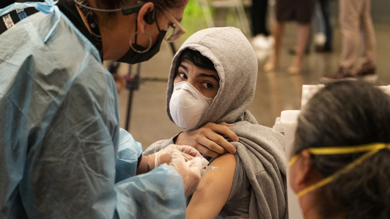 A student looks back at his mother, as he is vaccinated at a school-based COVID-19 vaccination clinic for students 12 and older in San Pedro, Calif., Monday, May 24, 2021. (AP Photo/Damian Dovarganes)
