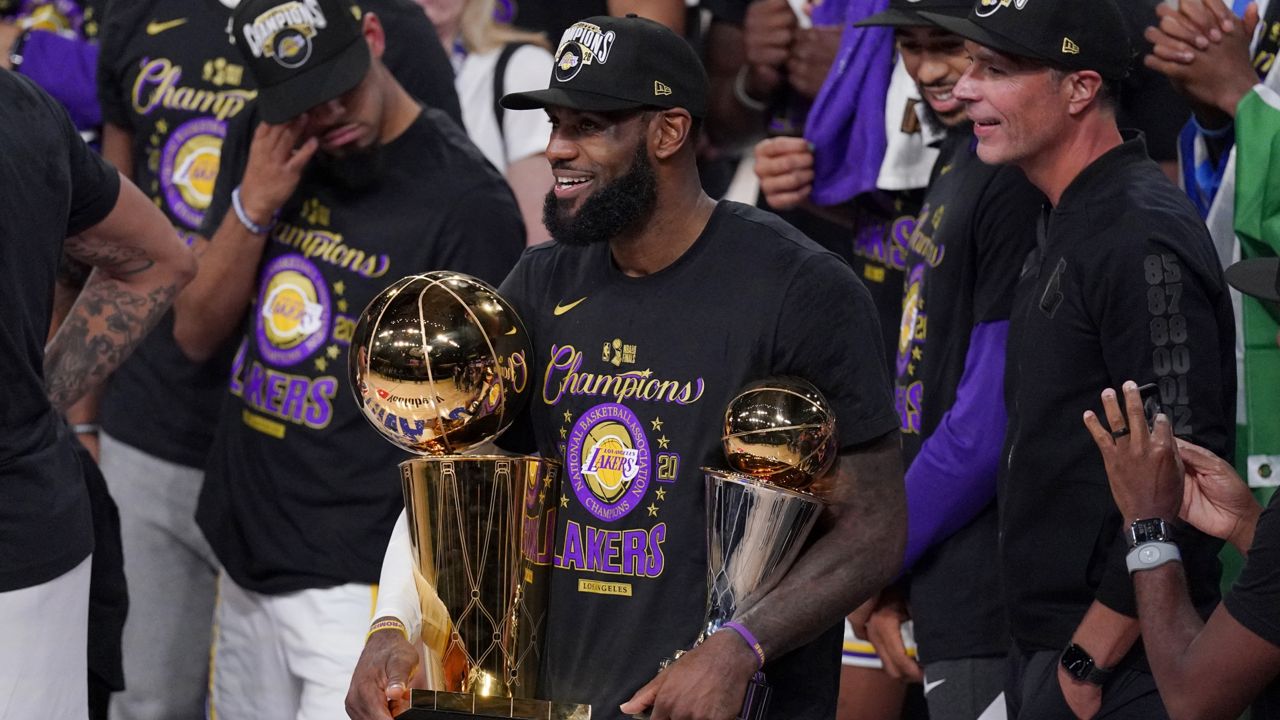 Los Angeles Lakers' LeBron James (23) holds the trophies as he celebrates with his teammates after the Lakers defeated the Miami Heat 106-93 in Game 6 of basketball's NBA Finals Sunday, Oct. 11, 2020, in Lake Buena Vista, Fla. (AP Photo/Mark J. Terrill)
