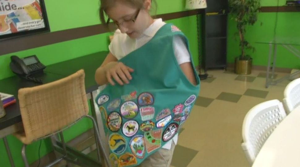 Girl Scout Bianca Ramsey shows off the patches on her Girl Scout vest October 10, 2019 (Spectrum News)