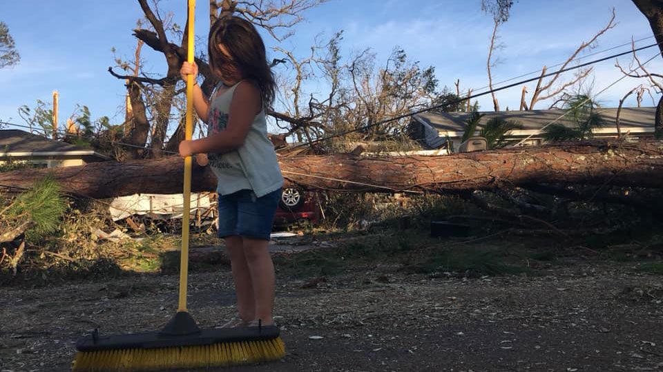 A young girl sweeps the street in front of her home in the Florida panhandle .