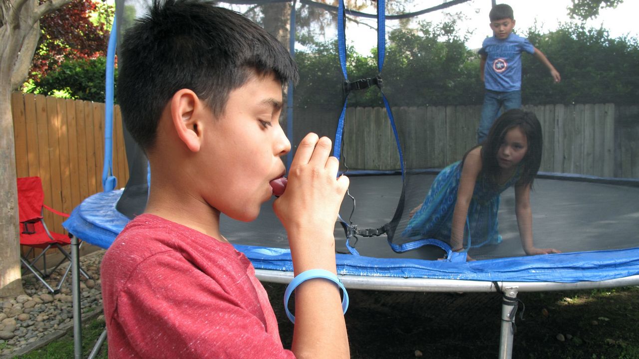 In this photo April 4, 2017 photo, Javier Sua demonstrates how he uses an inhaler at his home in Fresno, Calif. (AP Photo/Scott Smith)