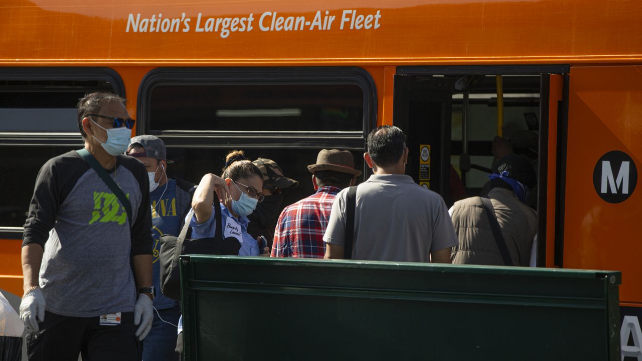 Los Angeles Metro commuters board a bus in Los Angeles on Thursday, May 14, 2020. (AP Photo/Damian Dovarganes)