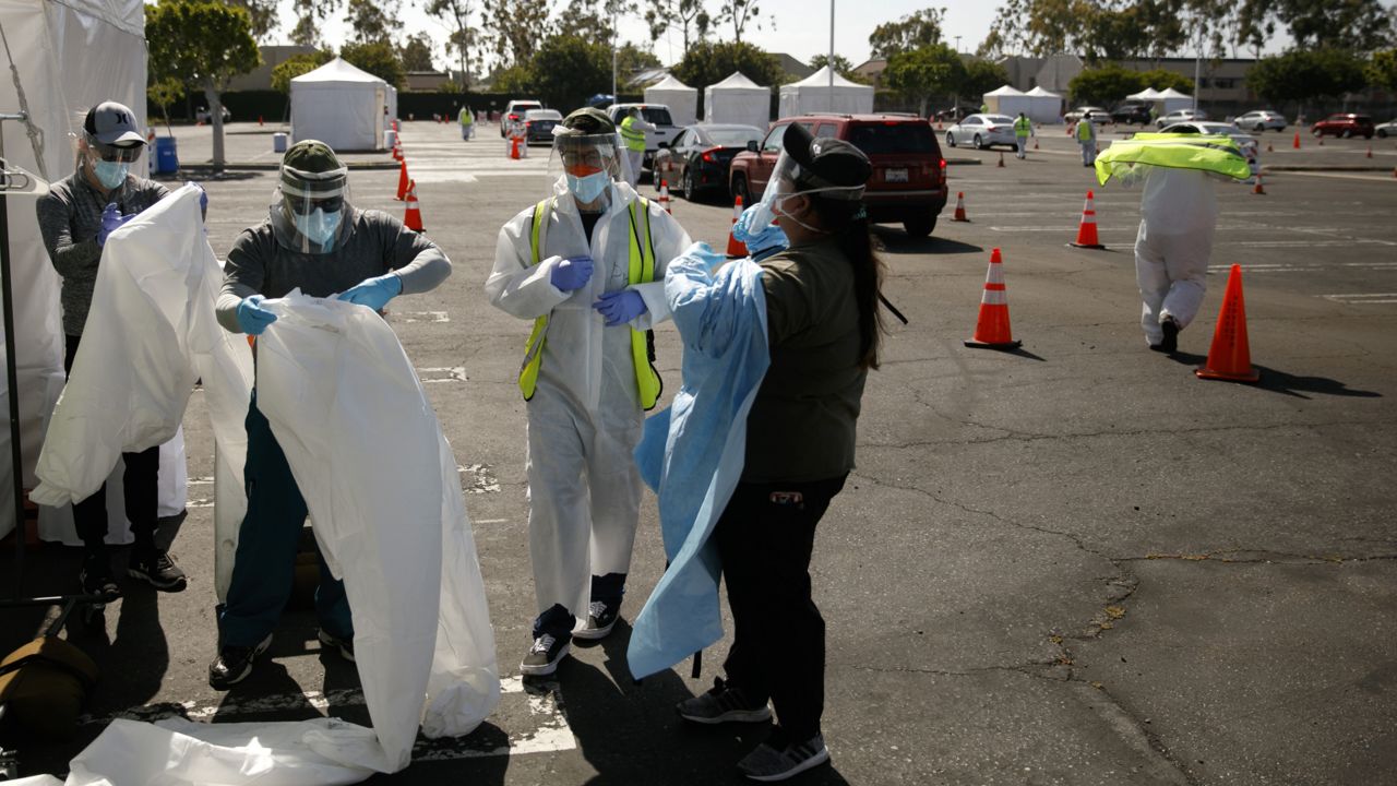 A group of volunteers put on protective suits at a city-run, drive-thru COVID-19 testing site in South Central Los Angeles on May 22, 2020. (AP Photo/Jae C. Hong, File