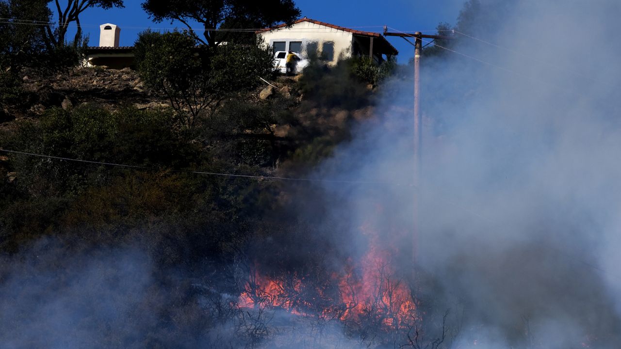 A wildfire burns near a home Wednesday, Oct. 13, 2021, in Goleta, Calif. (AP Photo/Ringo H.W. Chiu)