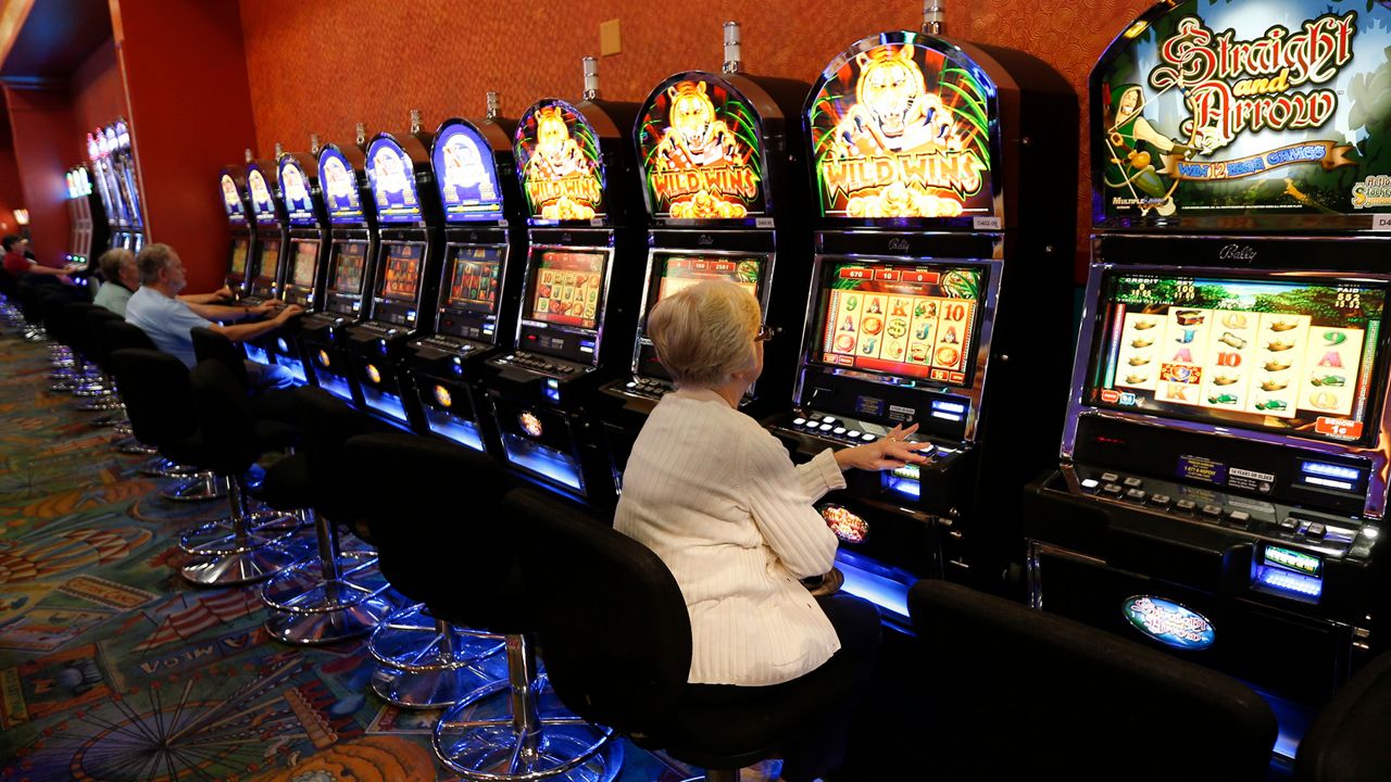 A person wearing a white sweater sits at a video lottery terminal.