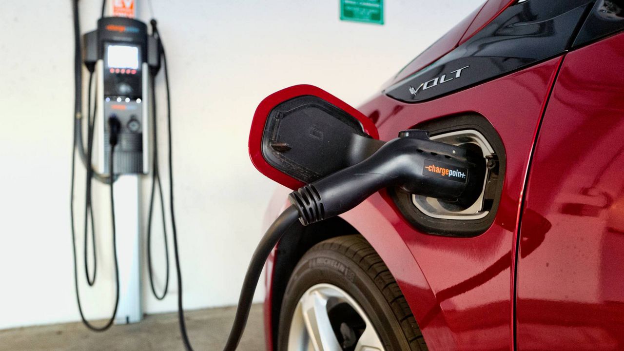 This Oct. 17, 2018, photo shows a Chevrolet Volt hybrid car charging at a ChargePoint charging station at a parking garage in Los Angeles. (AP Photo/Richard Vogel, File)