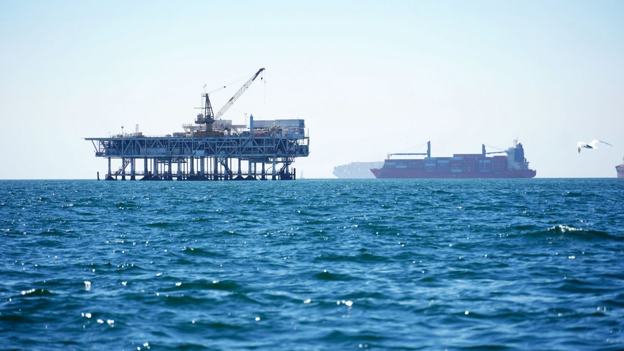 Dozens of cargo vessels are anchored offshore, sharing space with about a half dozen oil platforms, before heading into the Los Angeles-Long Beach port on Oct. 5, 2021. (AP Photo/Eugene Garcia) 