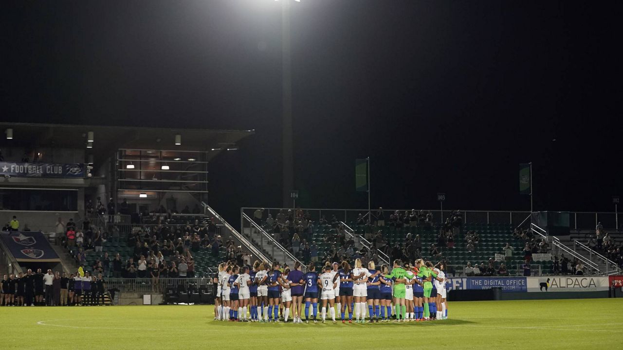 North Carolina Courage and Racing Louisville FC players pause and gather at midfield during the first half of an NWSL soccer match in Cary, N.C., Wednesday, Oct. 6, 2021. (AP Photo/Gerry Broome)