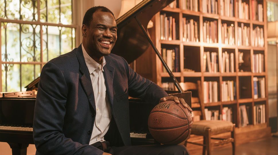 Former San Antonio Spurs basketball star David Robinson sits at a piano with a basketball and smiles (Courtesy: Josh Huskin)