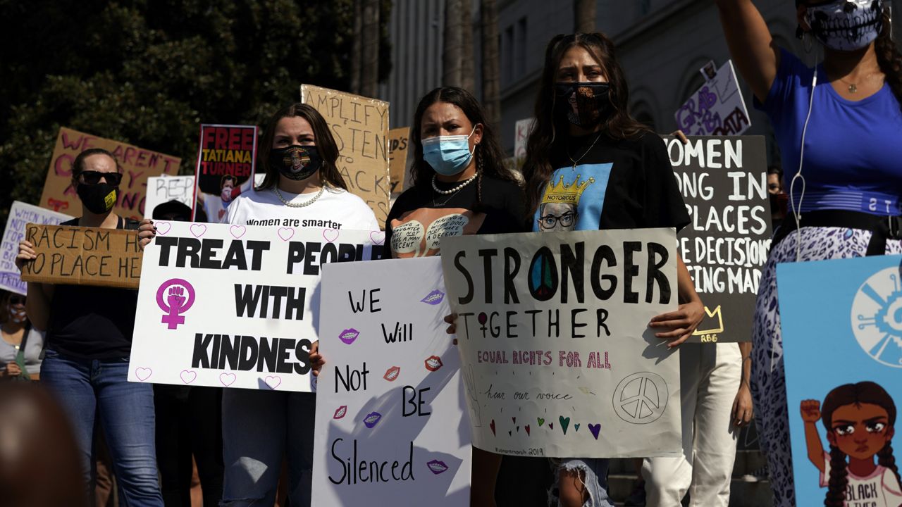 Demonstrators hold signs during a Women's March Saturday, Oct. 17, 2020, in Los Angeles. (AP Photo/Marcio Jose Sanchez)