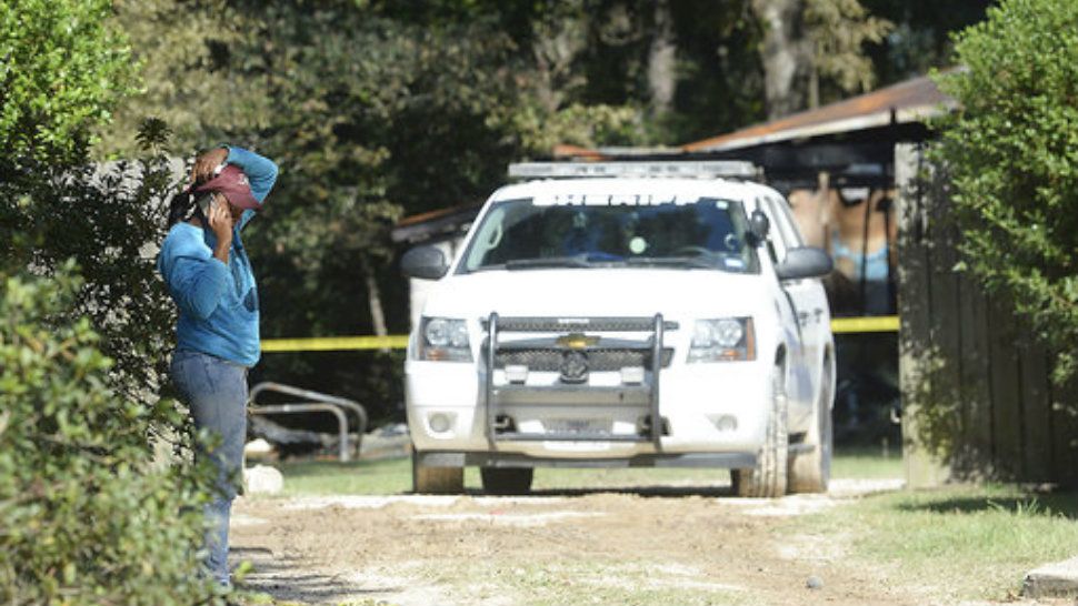 A family friend talks on her cell phone as Hardin County Sheriff and others continue their investigation at the scene of a fatal fire in Silsbee, Texas, Wednesday, Oct. 18, 2017. (Kim Brent/The Beaumont Enterprise via AP)
