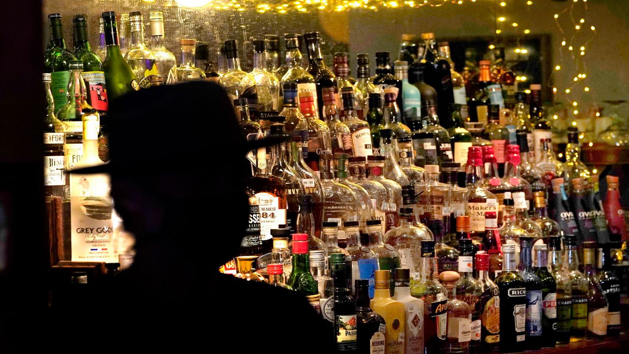 A sillouette of a man in a hat in front of a bar