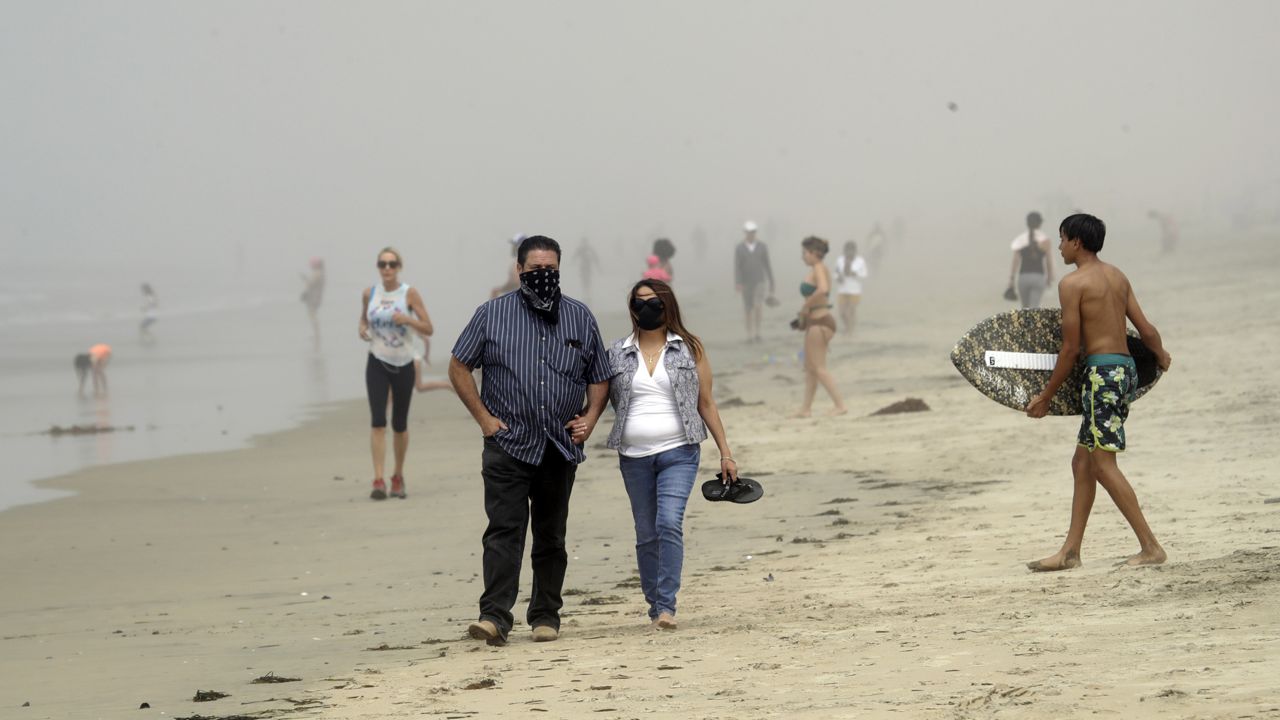 People wear masks as they walk on the beach in Huntington Beach, Calif. on April 26, 2020.  (AP Photo/Marcio Jose Sanchez,File)