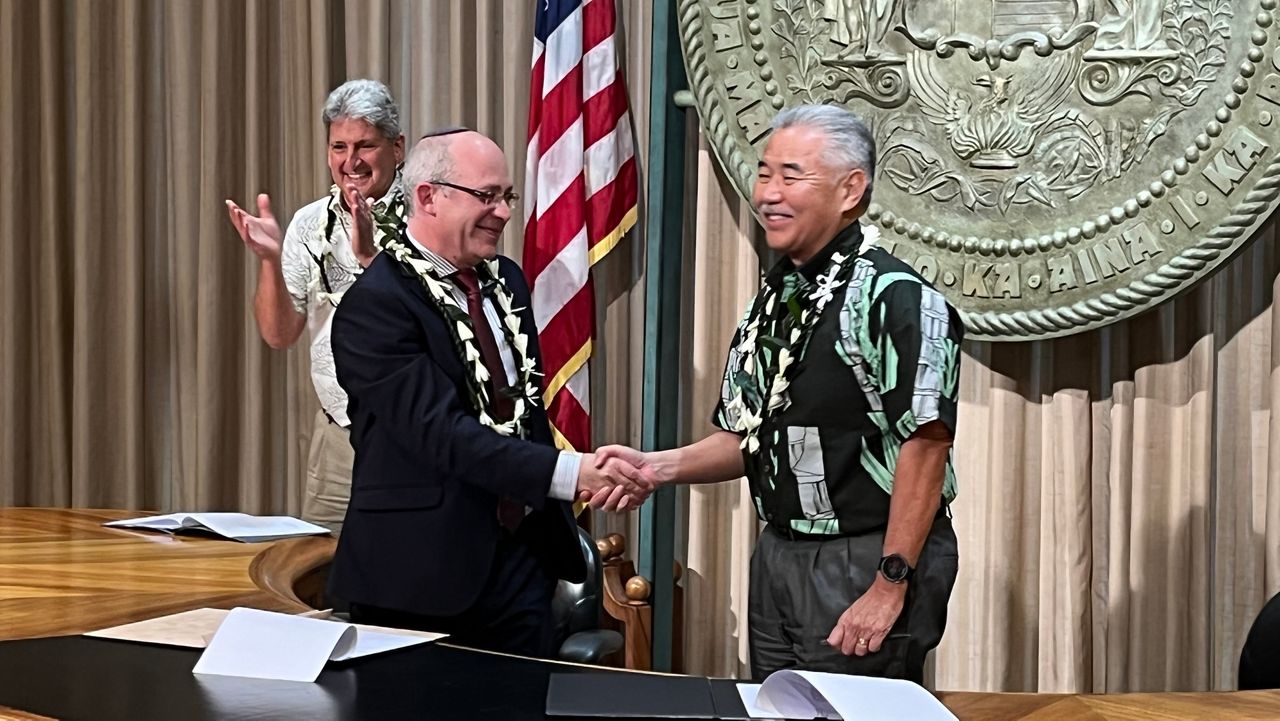 Consul General of Israel in Los Angeles Hillel Newman and Gov. David Ige shake hands after signing a memorandum of understanding between Israel and Hawaii while University of Hawaii president David Lassner applauds in the background. (Spectrum News/Michael Tsai)