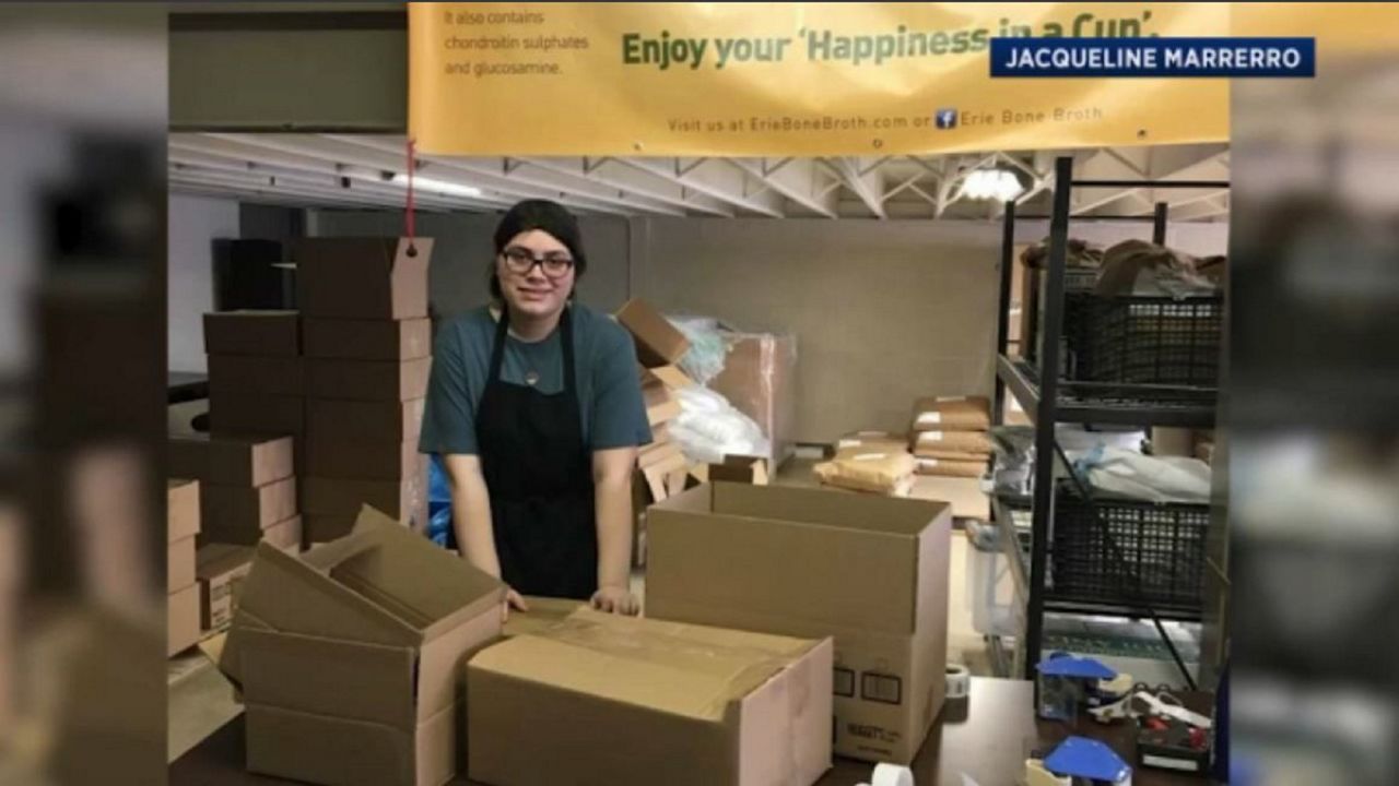 A woman stands behind multiple cardboard boxes