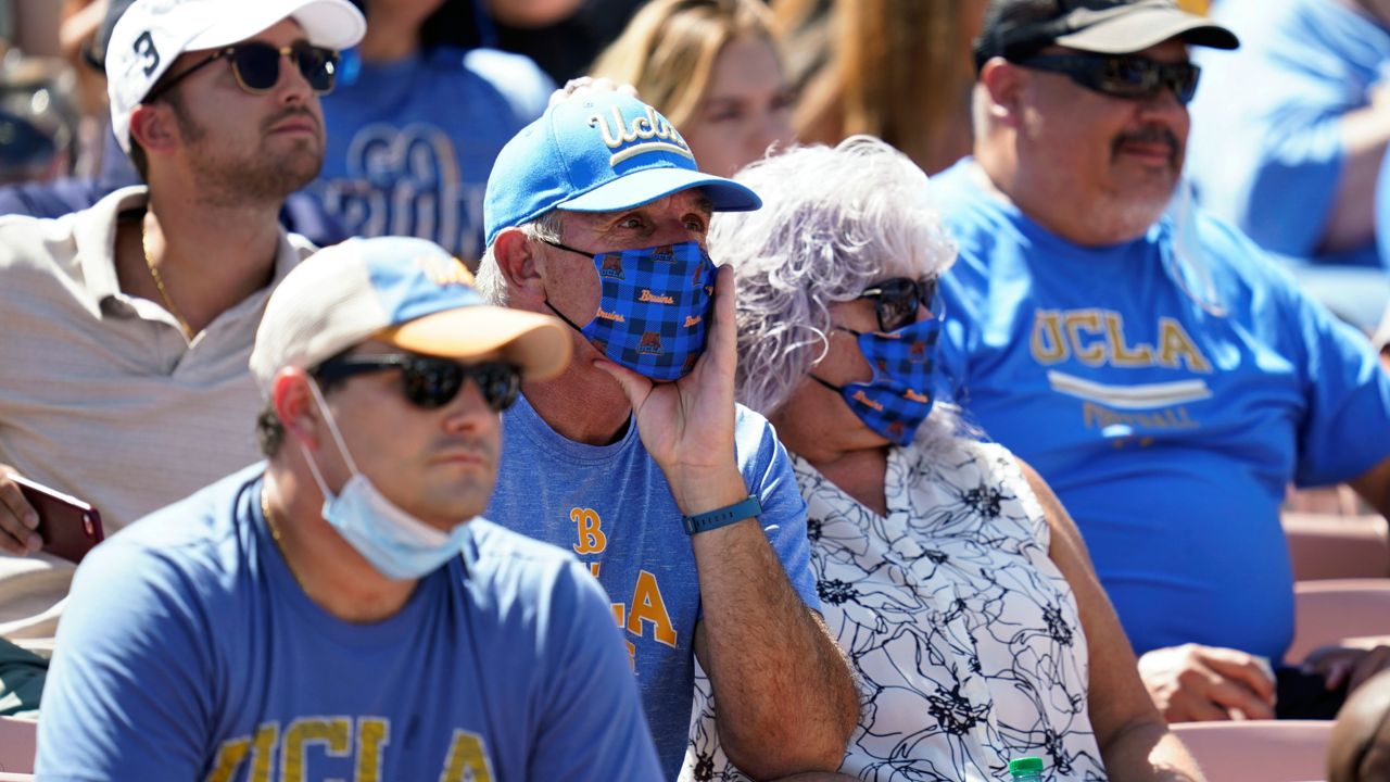 Fans, some wearing masks, sit in the stands during an NCAA college football game between Hawaii and UCLA on Saturday, Aug. 28, 2021, in Pasadena, Calif. (AP Photo/Ashley Landis)