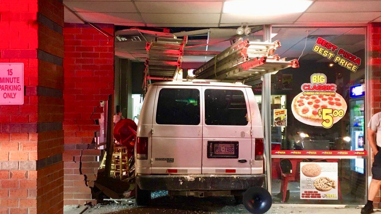 A white Ford work van crashed into the front of a pizza shop