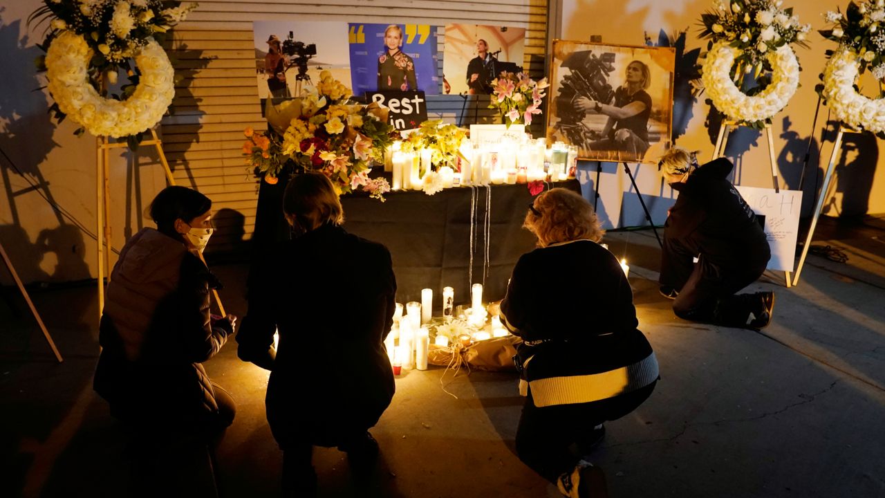 Attendees kneel at a candlelight vigil for the late cinematographer Halyna Hutchins, pictured in photographs, Sunday, Oct. 24, 2021, in Burbank, Calif. (AP Photo/Chris Pizzello)