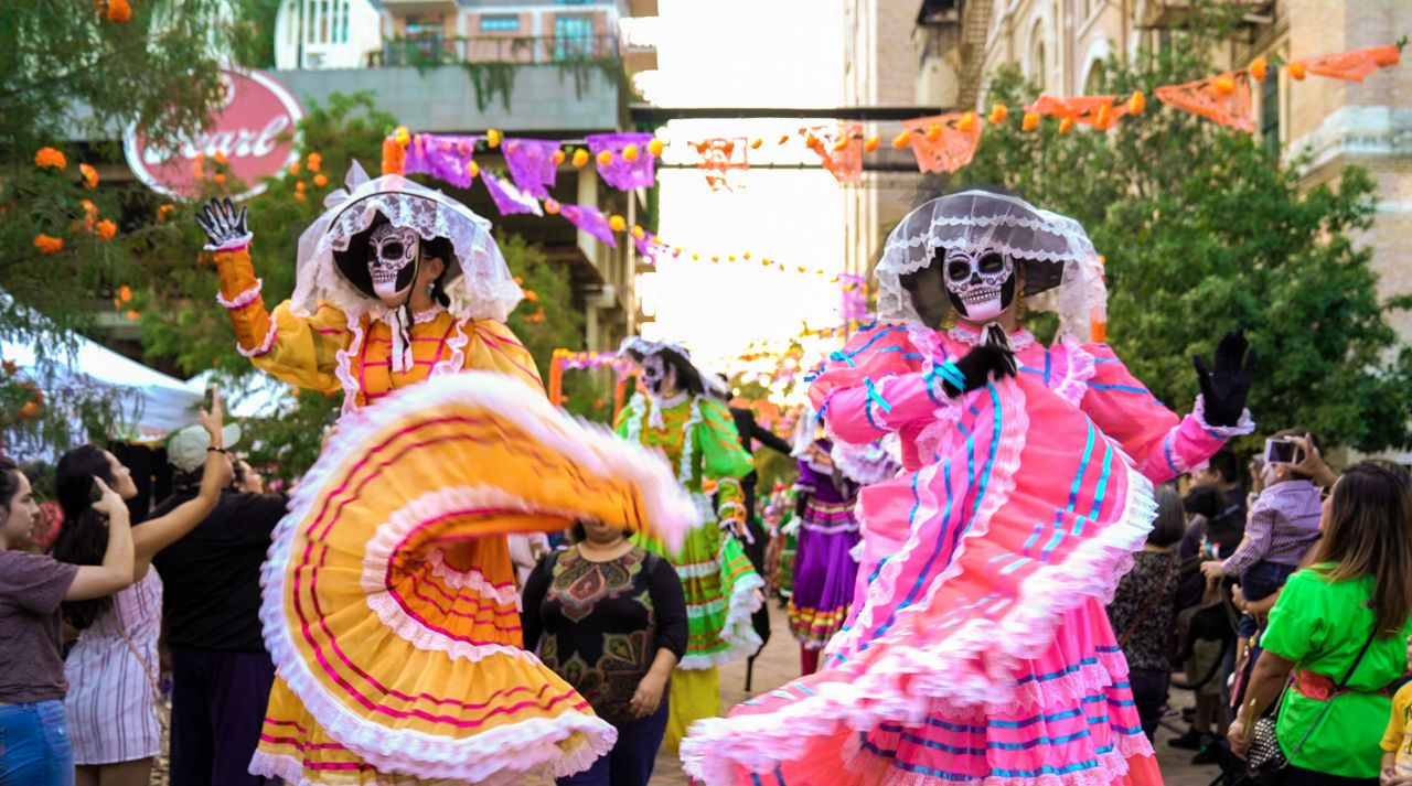 Two people in Dia de los Muertos costumes walk the Pearl during a procession (Spectrum News/File)