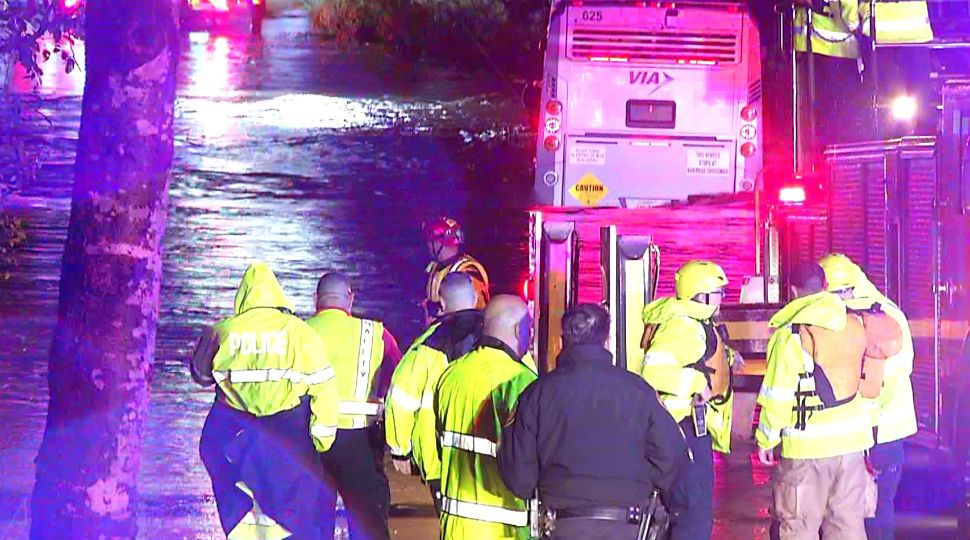 A group of authorities stand near a flooded area with high water where a VIA bus got stuck and 8 people were rescued October 24, 2019 (Stringer/Ken Branca)