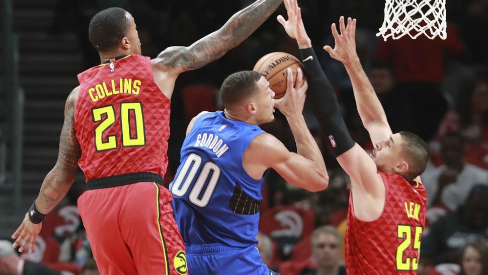 Atlanta Hawks forward John Collins (20) and center Alex Len (25) block a shot by Orlando Magic forward Aaron Gordon (00) during the first half of an NBA basketball game Saturday, Oct. 26, 2019, in Atlanta. (Curtis Compton/Atlanta Journal-Constitution via AP)