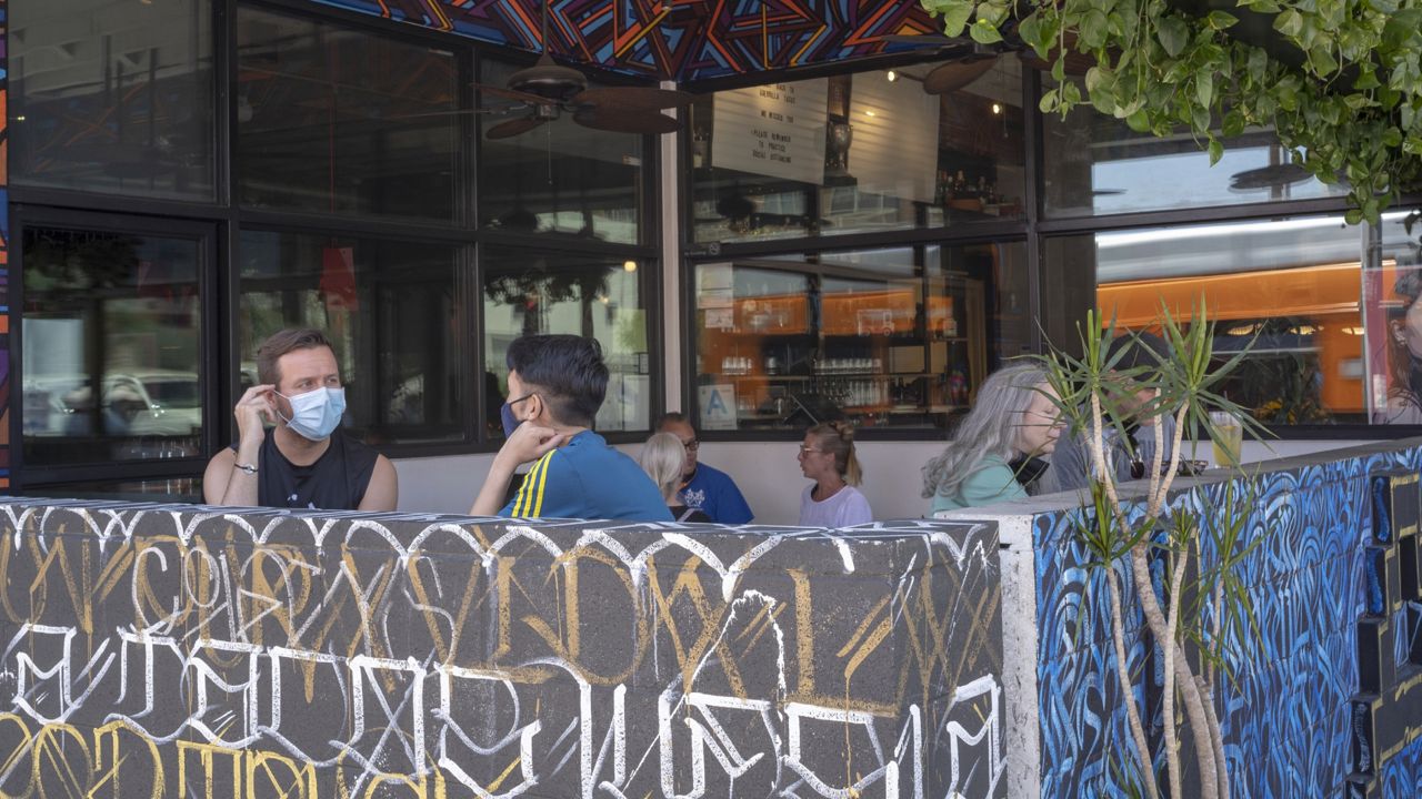 Patrons observing social distancing rules sit outdoors at the Guerrilla Tacos restaurant in Los Angeles, Friday, July 3, 2020. (AP Photo/Damian Dovarganes)