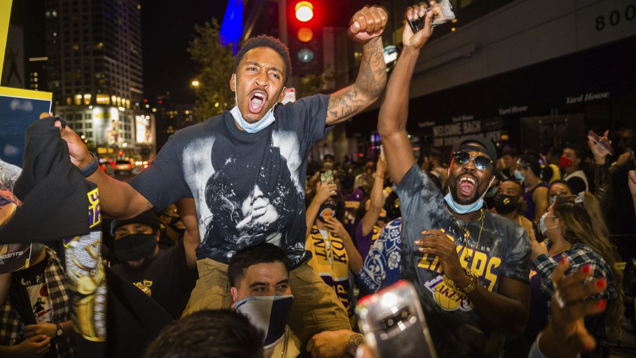 Fans celebrate, Sunday, Oct. 11, 2020, in Los Angeles, after the Los Angeles Lakers defeated the Miami Heat in Game 6 of basketball's NBA Finals to win the championship. (AP Photo/Jintak Han)