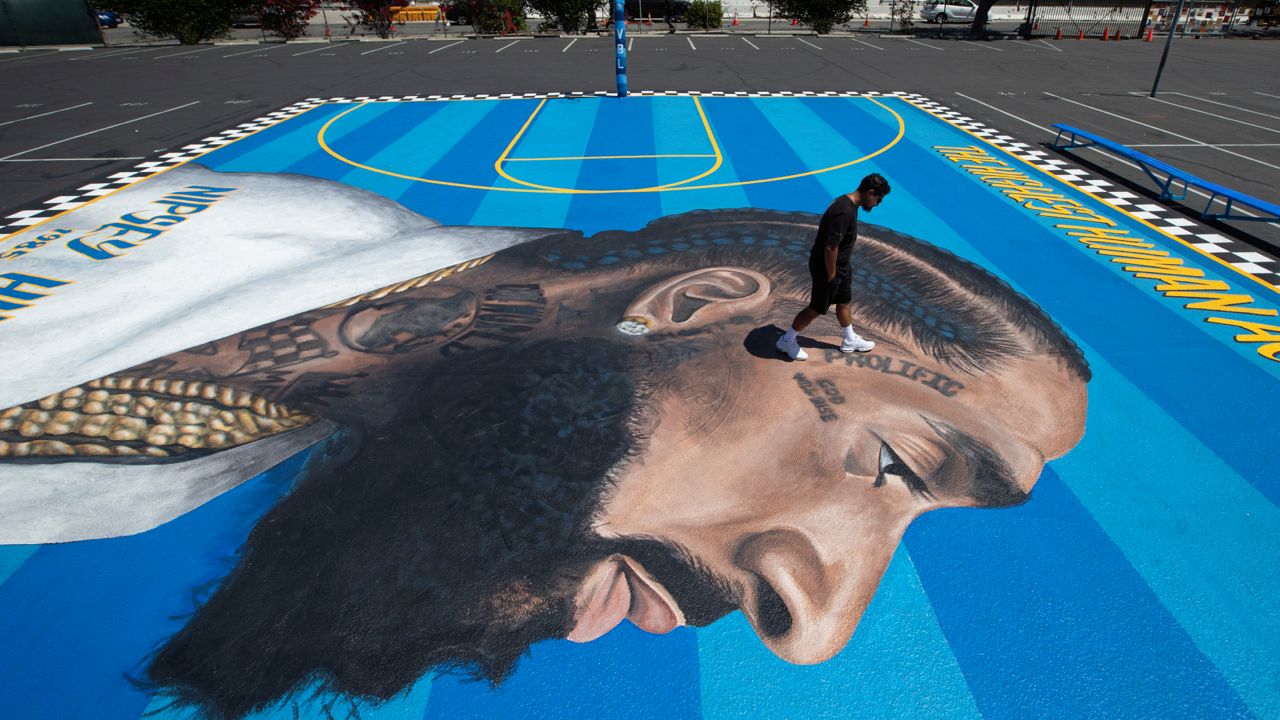 In this April 17, 2019 photo, mural artist Gustavo Zermeno Jr. walks on a basketball court mural he dedicated to slain rapper Nipsey Hussle in Los Angeles. (AP Photo/Jae C. Hong)