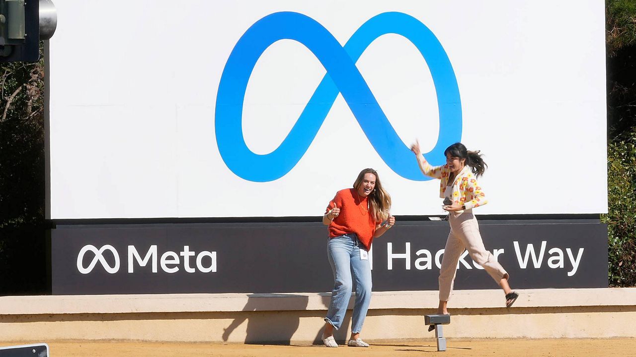 Facebook employees take a photo with the company's new name and logo outside its headquarters in Menlo Park, Calif., Oct. 28, 2021. (AP Photo/Tony Avelar)