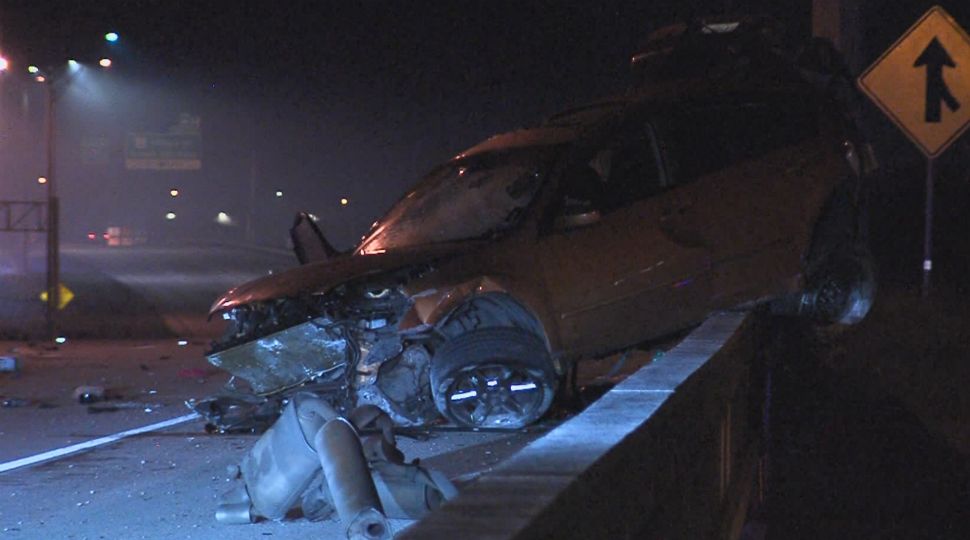 Car on I-37 overpass wall after rollover crash October 28, 2018 (Spectrum News)